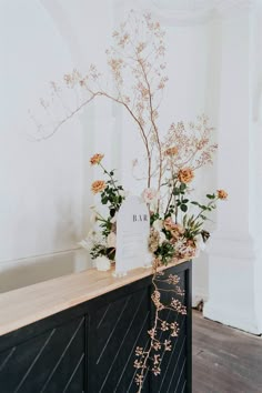 flowers are placed on top of a black cabinet