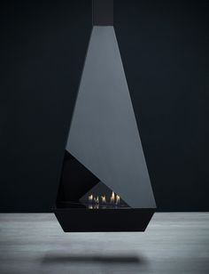 a modern fireplace with three lit candles in front of it on a dark background,