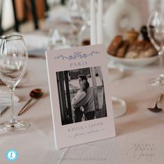 the table is set with wine glasses, silverware and a card that says paris