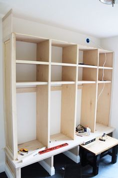 an unfinished bookcase is being built with plywood and glue on the bottom shelf