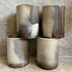 four gray and white vases sitting next to each other