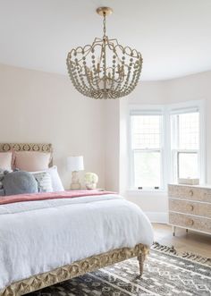 a bedroom with a chandelier hanging from the ceiling and a bed in front of a window