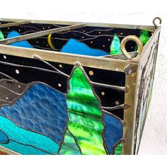 a stained glass box with mountains and stars on it