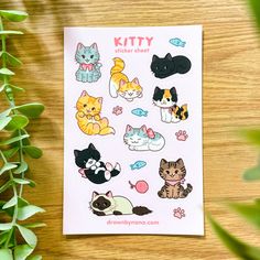 a sticker sheet with cats on it next to some green leaves and a potted plant