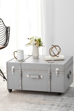 a trunk coffee table with two mugs on it and a vase filled with flowers