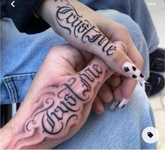 two people with tattoos on their hands holding one another's hand and the other has writing