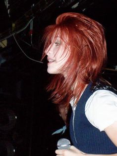 a woman with red hair holding a microphone