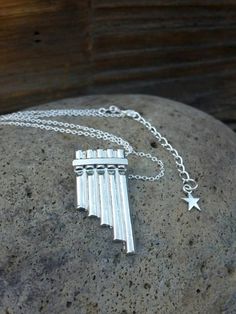 a small silver musical instrument necklace on a rock