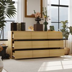 a wooden dresser sitting in front of a window next to a plant and potted plants