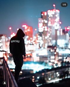 a person standing on top of a roof looking at the city lights in the distance