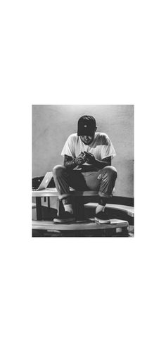 a black and white photo of a man sitting on top of a bench with his hands in his pockets