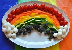 a white plate topped with veggies and carrots on top of a rainbow colored table cloth