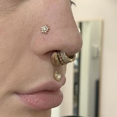 a close up of a person with piercings on their nose and ear rings in front of them