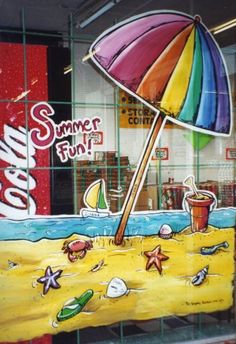 a window display with a colorful umbrella and soda on the beach in front of it