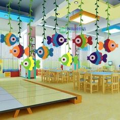 a classroom with colorful fish decorations hanging from the ceiling and tables in front of them