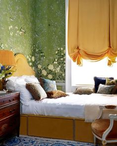 a bedroom with floral wallpaper and yellow drapes