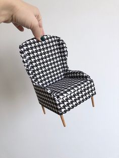 a hand is reaching for a chair with black and white houndskin pattern on it