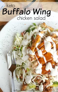 a white plate topped with lettuce and chicken covered in ranch dressing next to a fork