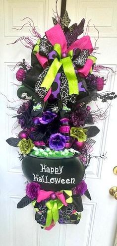 a halloween wreath on the front door decorated with purple, green and black ribbons that say happy halloween