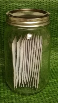 a glass jar filled with lots of white papers on top of a green tablecloth