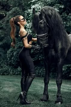 a woman standing next to a black horse