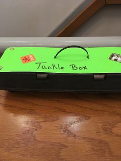 a black and green box with some stickers on it's lid sitting on a wooden table