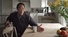 a man sitting at a kitchen table with a coffee mug