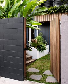 an entrance to a house with plants and stepping stones in the grass next to it