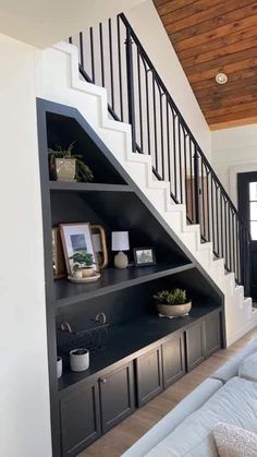 a living room filled with furniture next to a stair case and bookshelf on top of a wooden floor