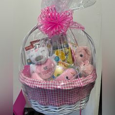 a pink teddy bear sitting in a basket filled with baby items and other stuff animals