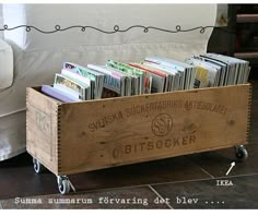 a wooden crate filled with books sitting on top of a tiled floor next to a white couch