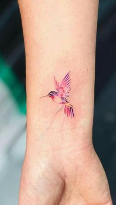 a small tattoo on the wrist of a woman's hand with a hummingbird