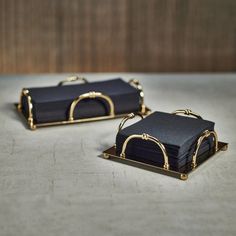 two black and gold serving trays sitting on top of a table next to each other