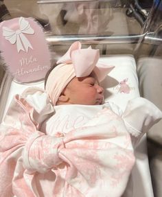 a baby girl is sleeping in her crib with a pink bow on it's head