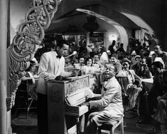 an old photo of a man playing the piano in front of a group of people