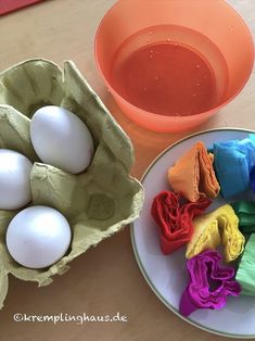 two bowls filled with different colored dyes next to an egg in a carton