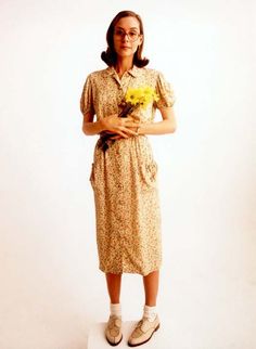 a woman standing on top of a white surface holding a bouquet of flowers in her hands