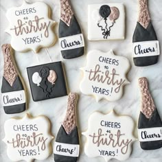 decorated cookies with wine bottles and balloons on a white tablecloth covered in icing