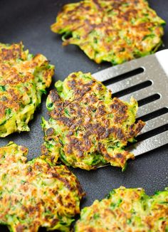 some food is being cooked on a grill with a spatula in the foreground