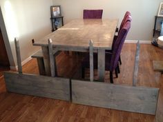 a dining room table with purple chairs and wooden planks on the floor in front of it