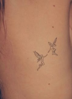 a small tattoo on the back of a woman's stomach with two birds flying above it