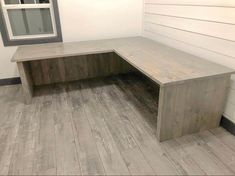 a wooden bench sitting on top of a hard wood floor next to a window in a room