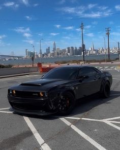 a black sports car parked in a parking lot with the city skyline in the background