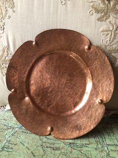 a large metal plate sitting on top of a green tablecloth covered floor next to a white pillow