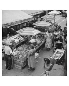 an old black and white photo of people buying food