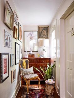 the hallway is decorated with art and pictures on the wall, along with a chair