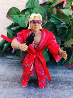 the action figure is holding a microphone in one hand and wearing a red kimono