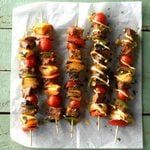 several skewers of meat and vegetables sitting on a napkin next to each other