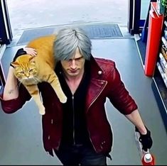 a man holding a cat in his arms while walking down the street from a convenience store