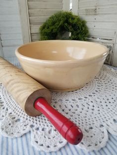 a wooden rolling pin sitting on top of a table next to a bowl